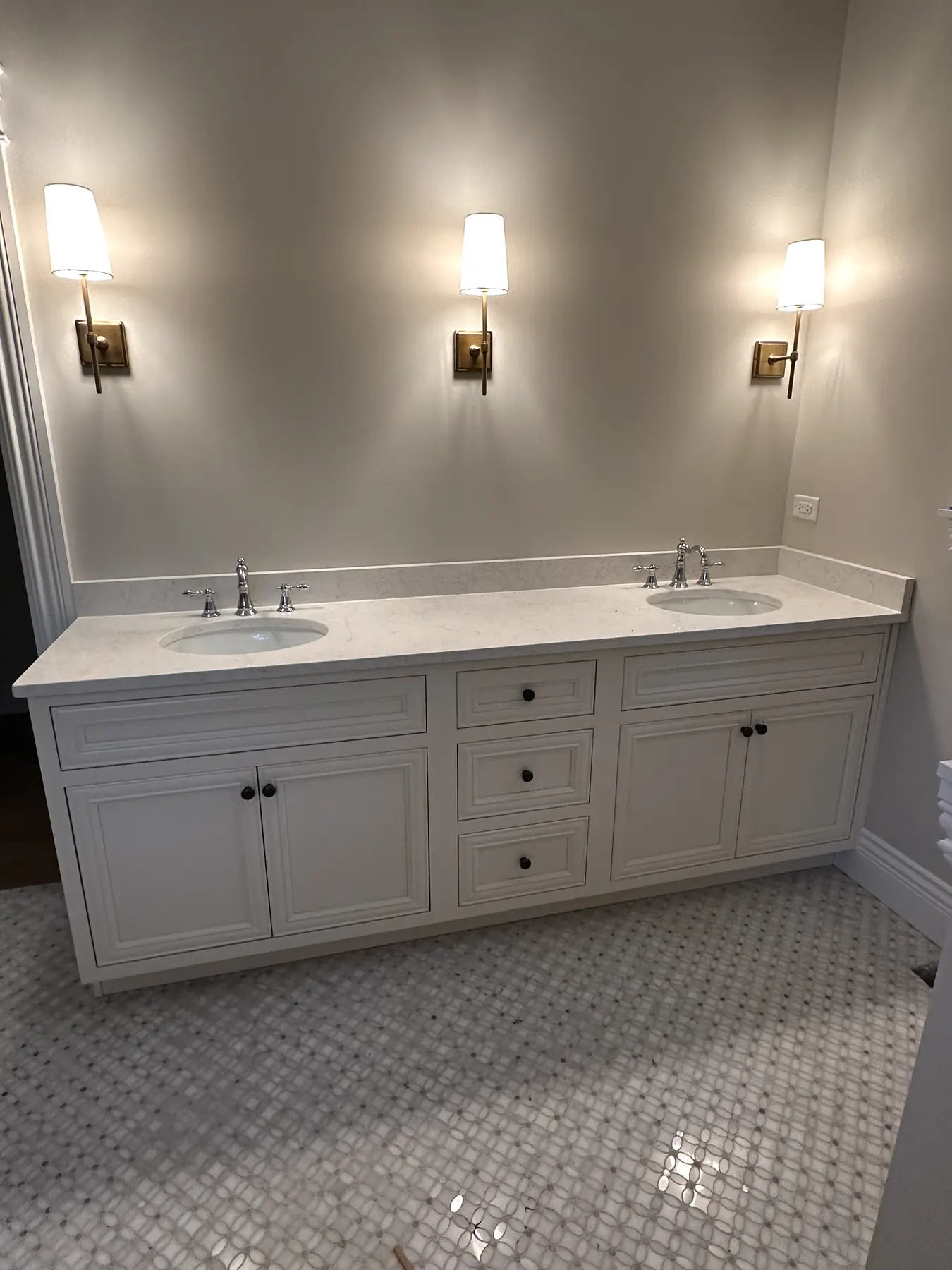 Double vanity with wall sconces and stone countertop