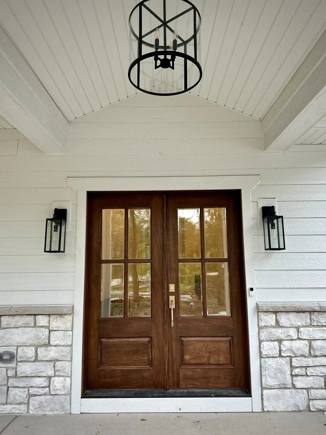 Wood double entry doors beneath a vaulted porch ceiling